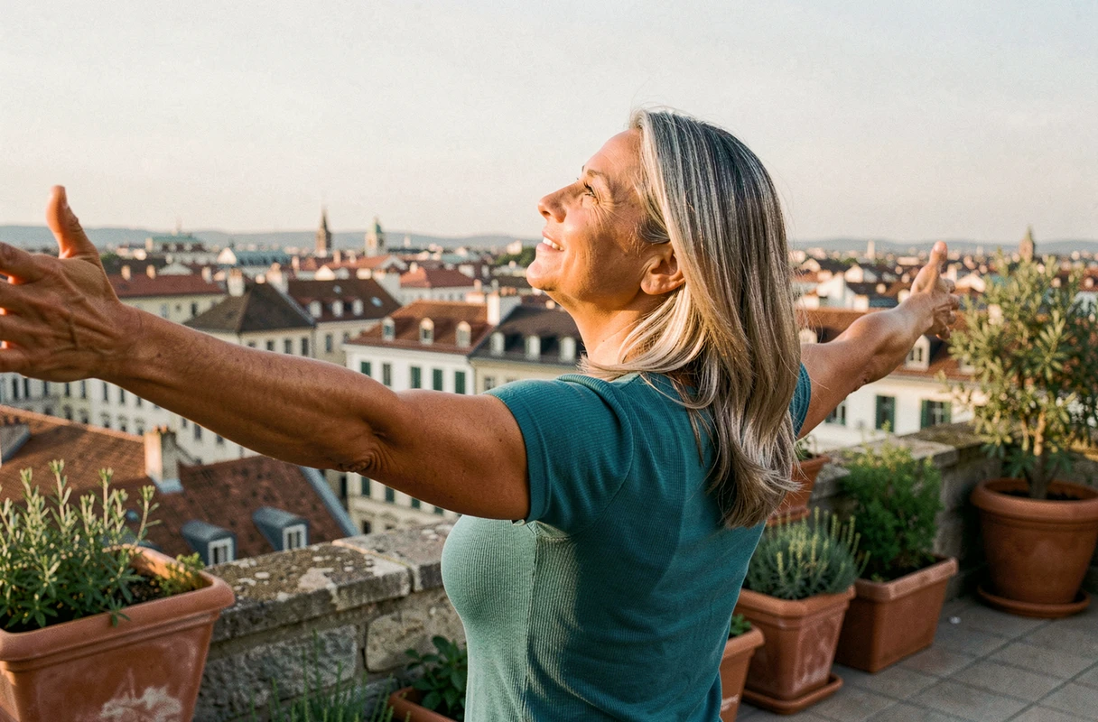 Femme épanouie aux bras ouverts sur une terrasse avec vue sur une ville européenne, symbolisant le rayonnement et l'énergie positive